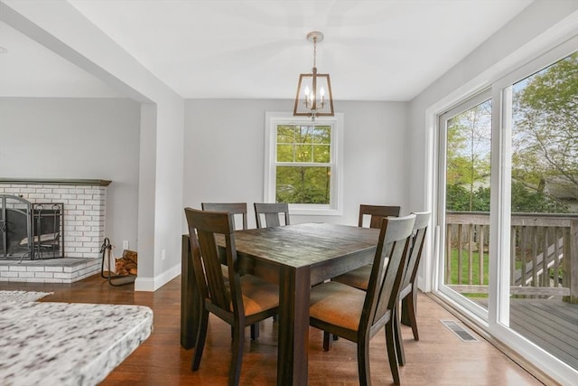dining room featuring plenty of natural light, wood finished floors, baseboards, and a chandelier