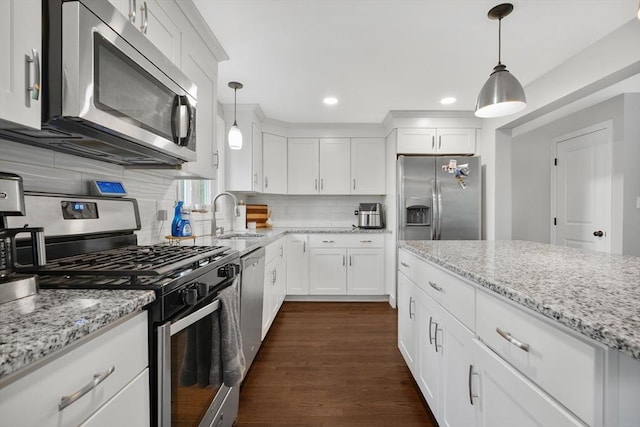 kitchen with appliances with stainless steel finishes, a sink, white cabinets, backsplash, and recessed lighting