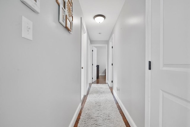 hallway featuring baseboards and wood finished floors