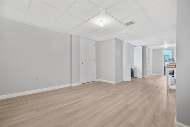 empty room featuring a paneled ceiling, light wood-style floors, and baseboards