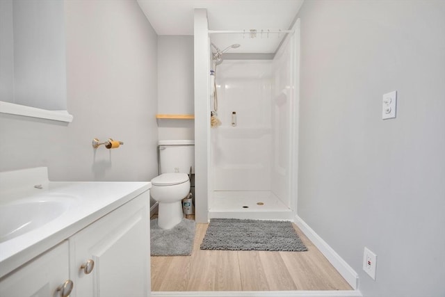 full bath featuring wood finished floors, a stall shower, toilet, vanity, and baseboards