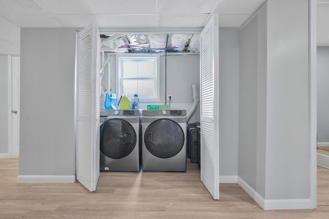 laundry area with separate washer and dryer, wood finished floors, and baseboards