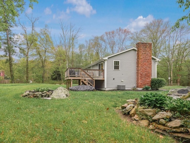 rear view of house with a deck, stairs, a chimney, and a lawn