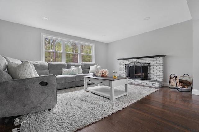 living room featuring dark wood-type flooring, a fireplace, baseboards, and recessed lighting