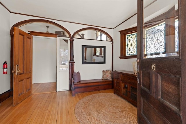 foyer with crown molding, light wood-style flooring, and vaulted ceiling