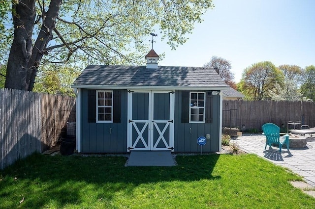view of shed featuring a fenced backyard and a fire pit