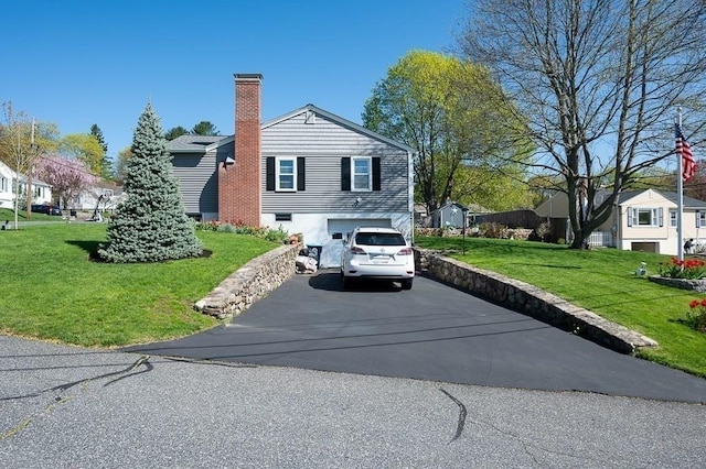 view of property exterior with a residential view, an attached garage, aphalt driveway, a chimney, and a yard