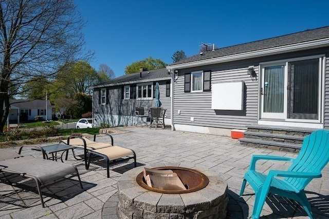rear view of house featuring roof with shingles, a patio area, entry steps, and an outdoor fire pit