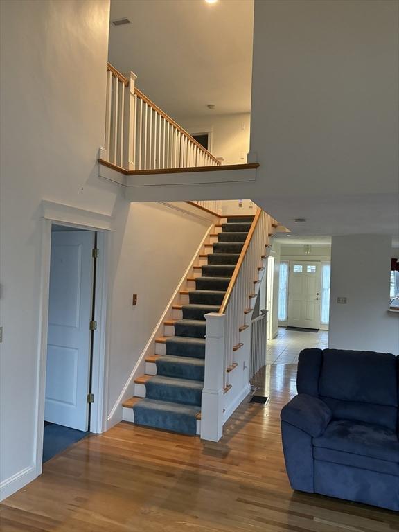 stairway with hardwood / wood-style floors and a high ceiling