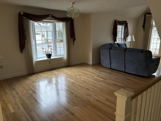 unfurnished living room with a healthy amount of sunlight, a notable chandelier, and hardwood / wood-style flooring