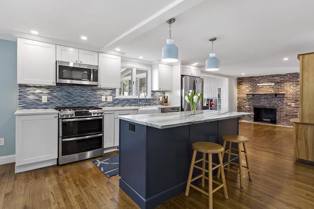50 Deerfield Rd, Barnstable, MA 02655 - kitchen with a fireplace, white cabinetry, dark wood finished floors, open floor plan, and stainless steel appliances