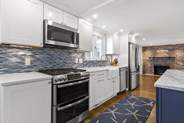 50 Deerfield Rd, Barnstable, MA 02655 - kitchen with white cabinetry, stainless steel appliances, dark wood-style floors, and a fireplace