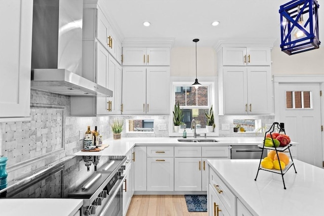 kitchen featuring white cabinets, a sink, light countertops, stove, and wall chimney exhaust hood