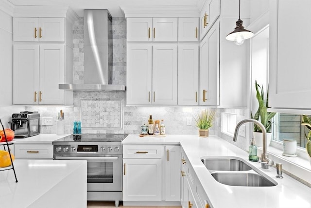 kitchen with light countertops, wall chimney exhaust hood, stainless steel electric stove, white cabinets, and a sink