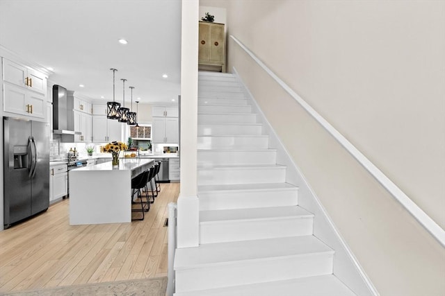 stairway with recessed lighting, an inviting chandelier, and wood finished floors