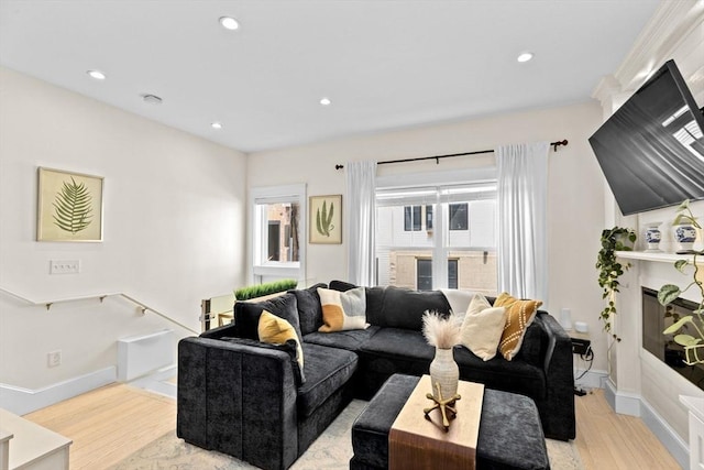 living area with recessed lighting, light wood finished floors, a glass covered fireplace, and baseboards