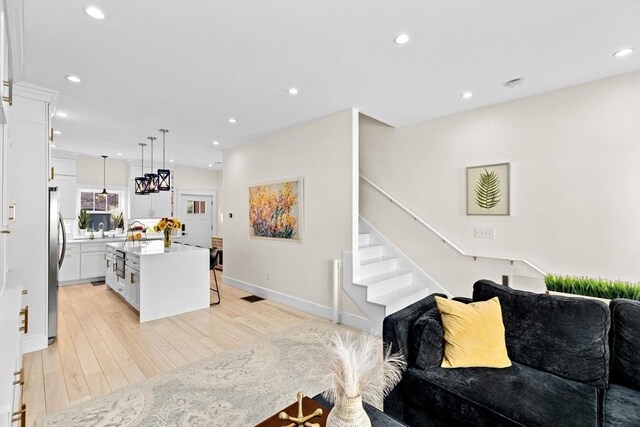 living room with stairs, recessed lighting, baseboards, and light wood finished floors