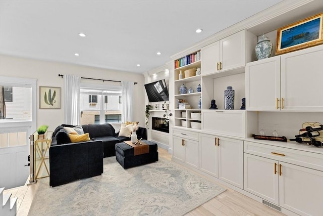 living area featuring a glass covered fireplace, recessed lighting, and light wood finished floors