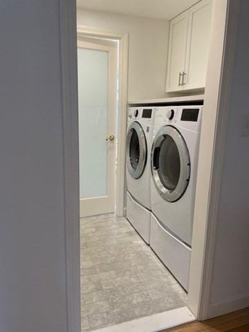 washroom with washer and dryer, cabinet space, and baseboards