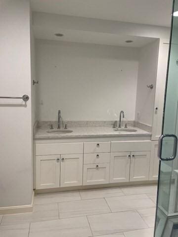 full bathroom featuring a sink, a shower stall, and baseboards