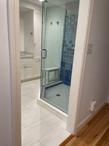bathroom with a stall shower, vanity, tile patterned floors, and baseboards