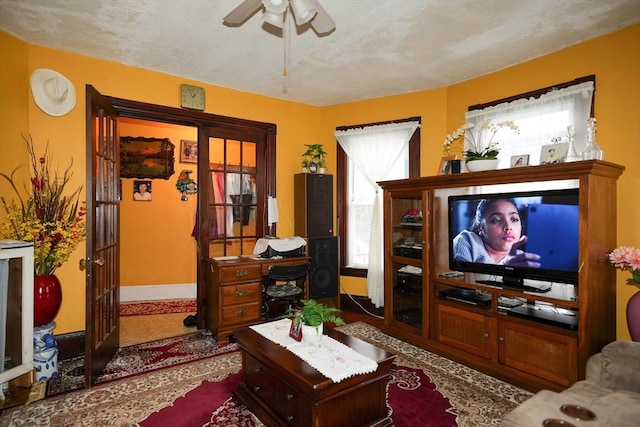 living room featuring ceiling fan and a textured ceiling