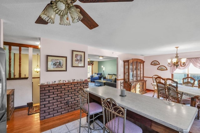 dining area featuring light wood-type flooring, a textured ceiling, and a notable chandelier