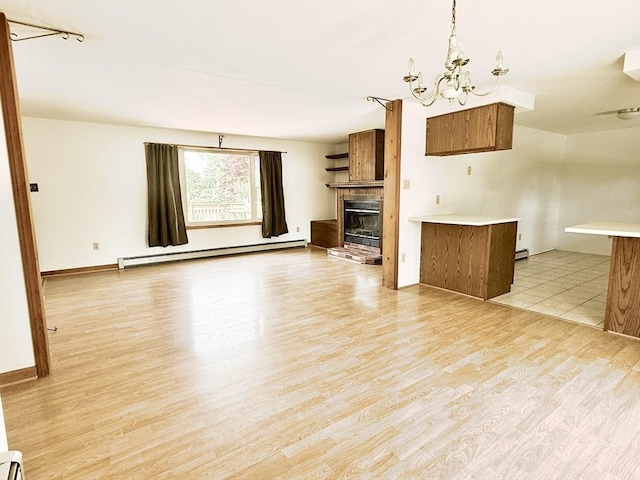 3 Teal Cir, Fairhaven, MA 02719 - unfurnished living room with a baseboard heating unit, a chandelier, light wood finished floors, a fireplace, and baseboard heating