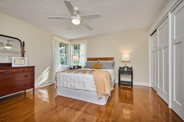 bedroom with ceiling fan, baseboard heating, a closet, and wood finished floors