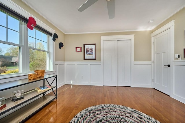 interior space with crown molding, a wainscoted wall, wood-type flooring, and a closet