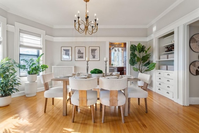 dining space featuring ornamental molding, an inviting chandelier, and light hardwood / wood-style flooring