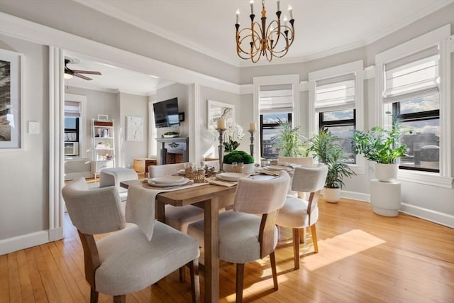 dining area with ornamental molding, ceiling fan with notable chandelier, and light hardwood / wood-style flooring