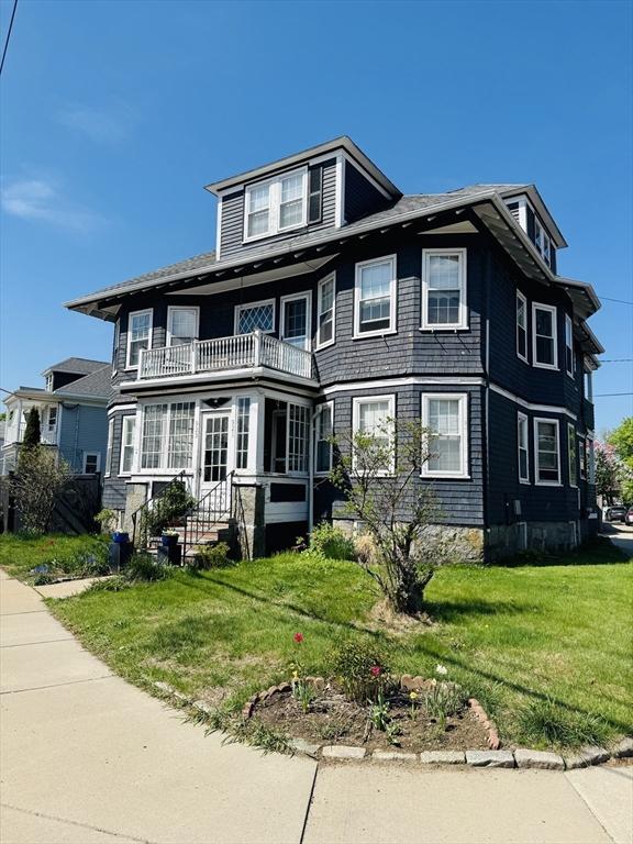 view of front of property with a balcony and a front lawn
