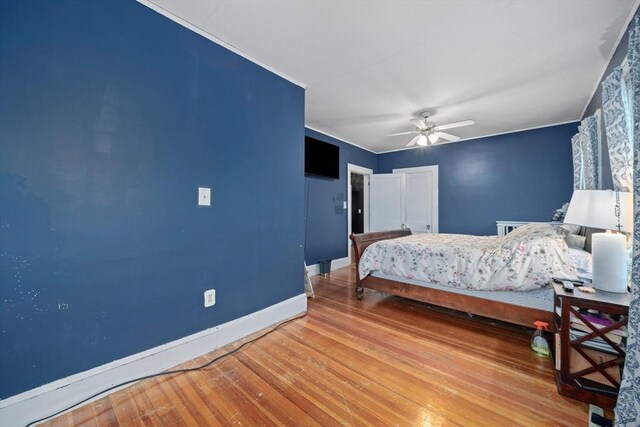 bedroom with wood-type flooring, baseboards, a ceiling fan, and crown molding