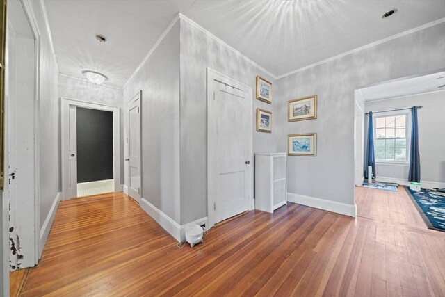 hall featuring hardwood / wood-style floors, baseboards, and crown molding