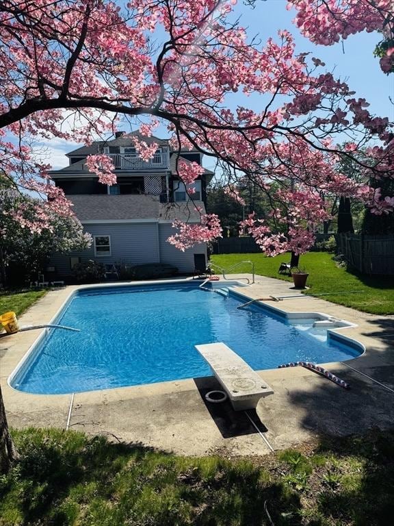 outdoor pool with a diving board and a patio