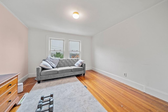 living room featuring light wood-style flooring, baseboards, and ornamental molding