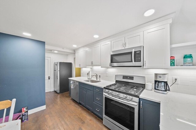 kitchen with stainless steel appliances, a sink, white cabinets, tasteful backsplash, and recessed lighting