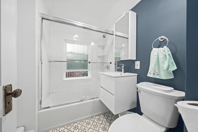 bathroom with toilet, vanity, and combined bath / shower with glass door