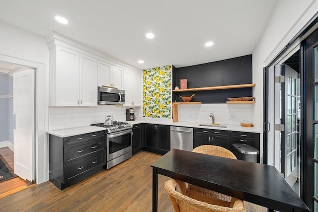 kitchen featuring appliances with stainless steel finishes, a sink, white cabinets, dark cabinets, and open shelves