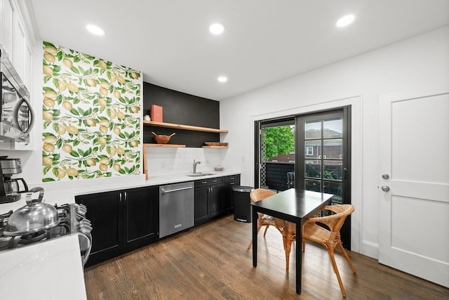 kitchen featuring appliances with stainless steel finishes, dark cabinets, light countertops, open shelves, and wood finished floors