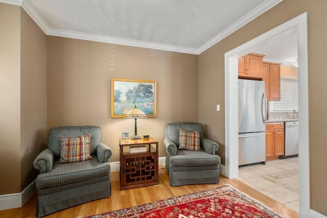 sitting room featuring light wood-style flooring, baseboards, and ornamental molding