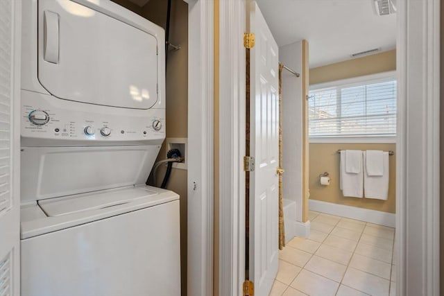 washroom with light tile patterned floors, visible vents, laundry area, and stacked washer / dryer