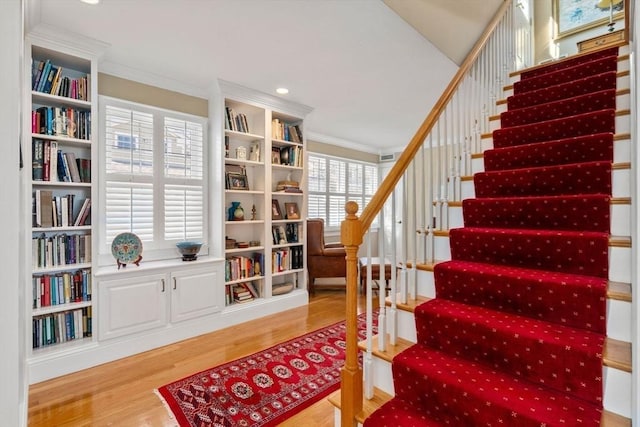 stairway with recessed lighting, wood finished floors, and ornamental molding