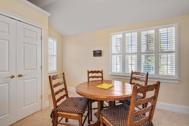 dining space with light carpet, lofted ceiling, and a healthy amount of sunlight