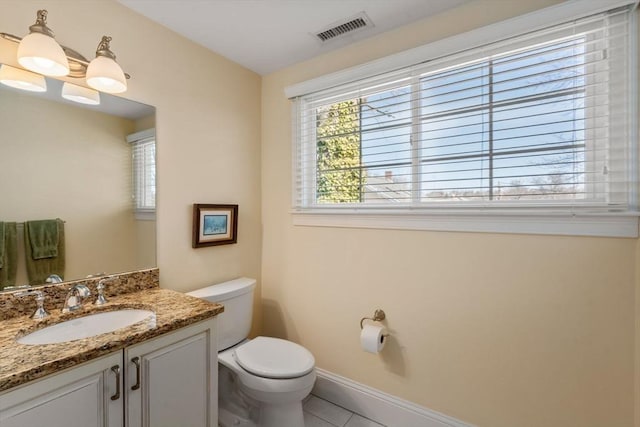 half bathroom with visible vents, toilet, tile patterned flooring, baseboards, and vanity