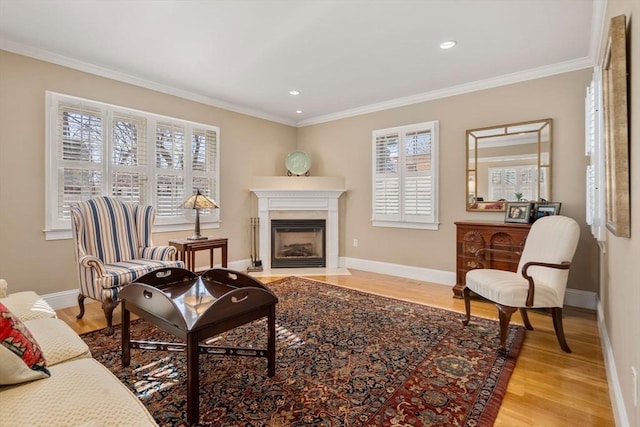 sitting room with light wood finished floors, a fireplace with flush hearth, baseboards, and ornamental molding