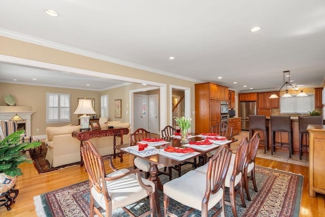 dining room featuring recessed lighting, a fireplace, light wood-type flooring, and ornamental molding