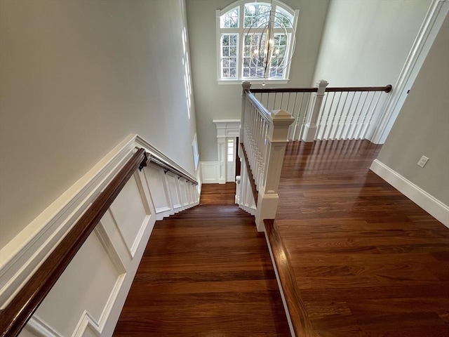 stairs featuring hardwood / wood-style flooring and an inviting chandelier