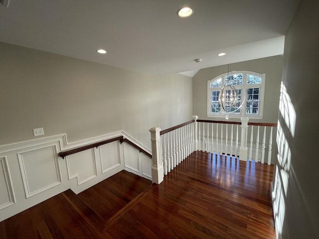 stairway featuring wood-type flooring and an inviting chandelier